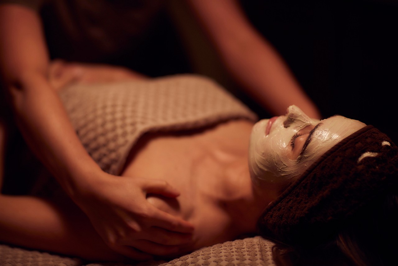Spa therapist giving a woman a face mask treatment.